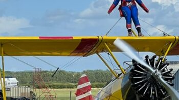 Harriet Bunn wing walking. Dress as Captain Marvel, strapped on top of a yellow biplane
